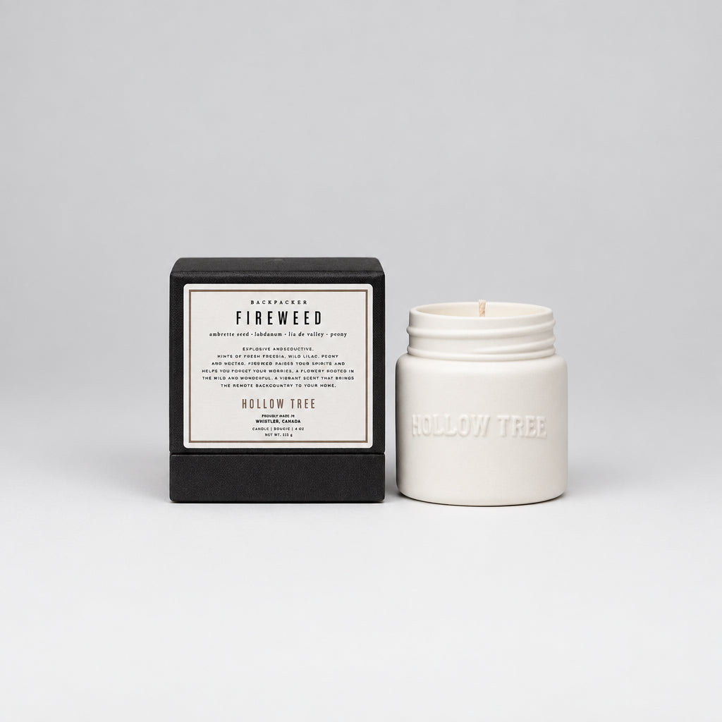 A white ceramic candle jar next to its black presentation box, both featuring the Hollow Tree brand and Fireweed scent label.