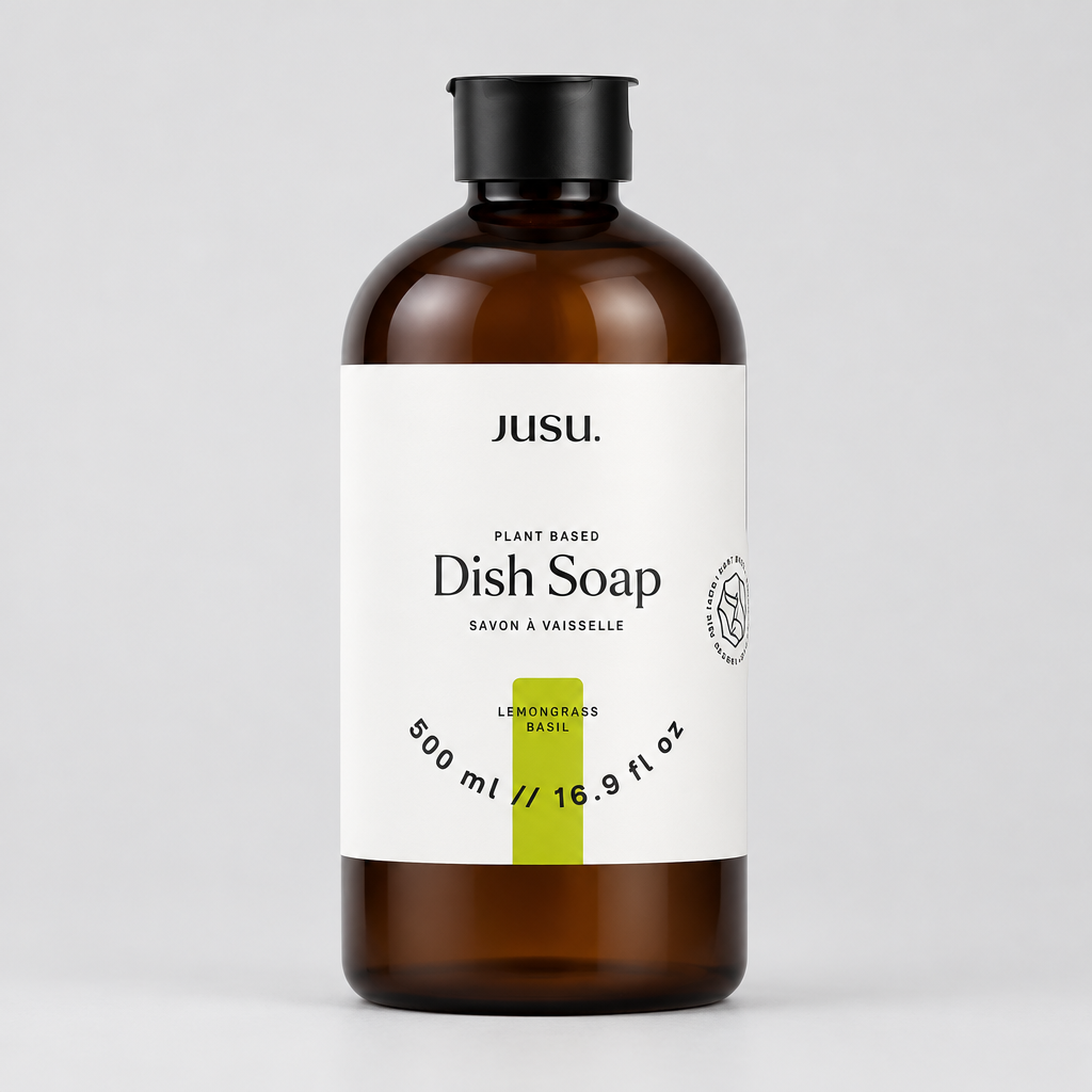 A 500 ml bottle of Jusu. Plant Based Dish Soap in Lemongrass Basil, featuring an amber brown bottle, black cap, and a white label with a green accent stripe.