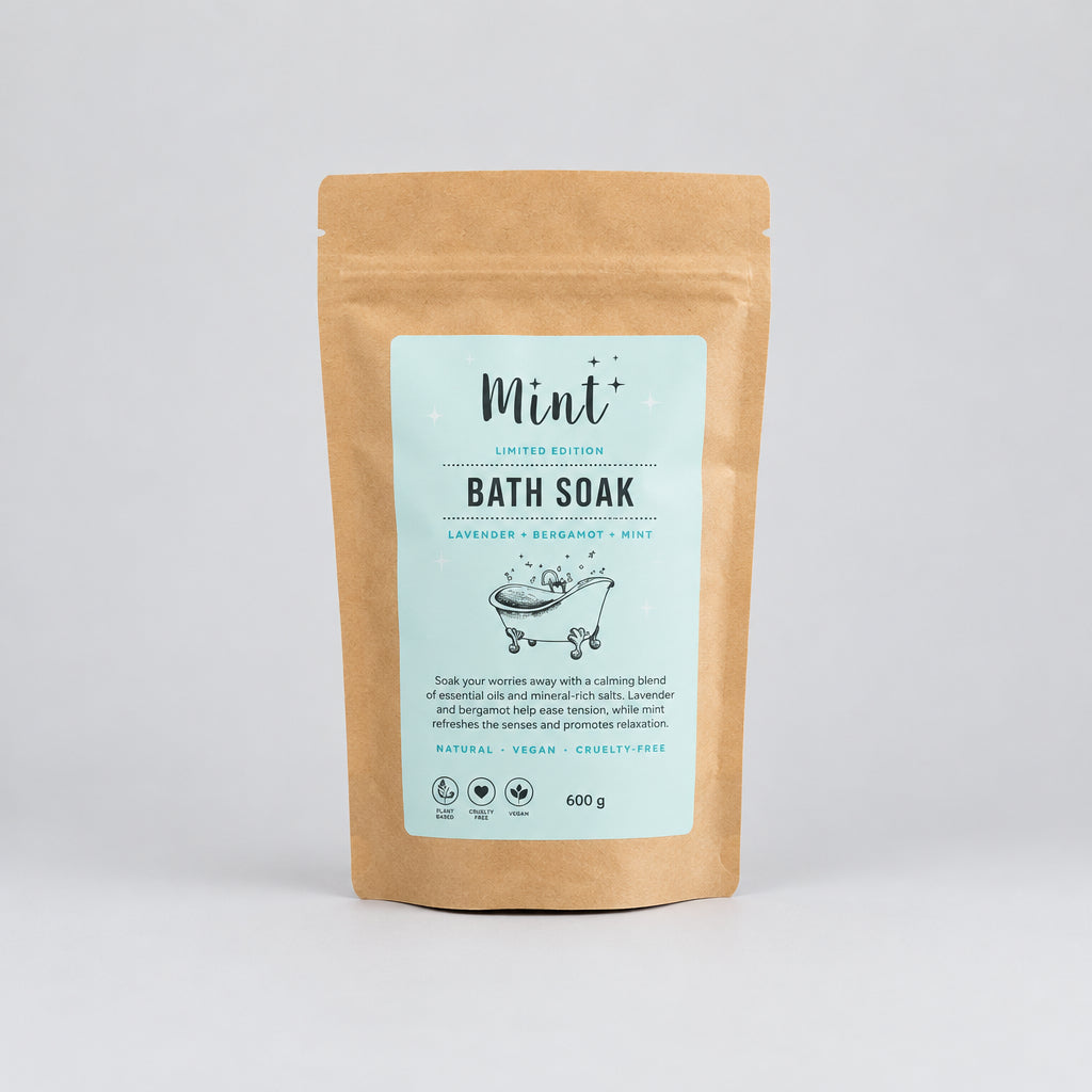 A stand-up pouch of Mint+ Bath Soak in Lavender + Bergamot, featuring a light blue label on a natural kraft paper bag.