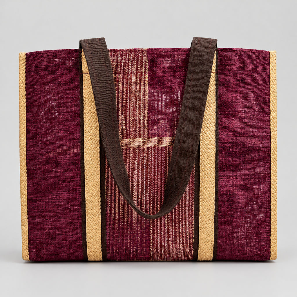 A woven tote bag made from deep magenta-purple and tan raffia-like material, featuring dark brown fabric shoulder straps, shown standing upright.