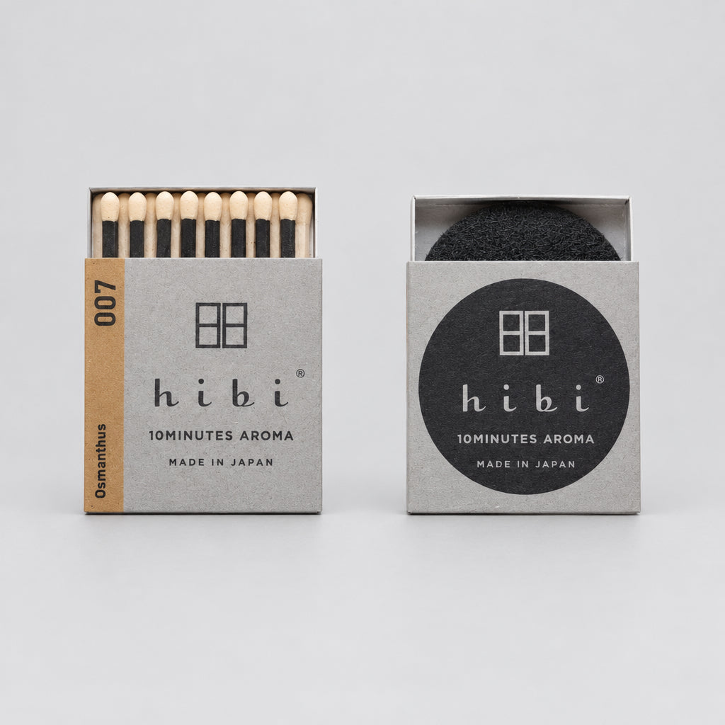 Two Hibi 10Minutes Aroma matchboxes on a white background, one open showing light wood matches and one closed with a black circular logo.